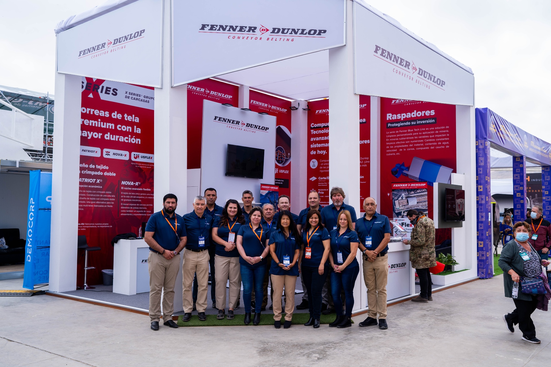 Equipo completo posando frente al stand corporativo